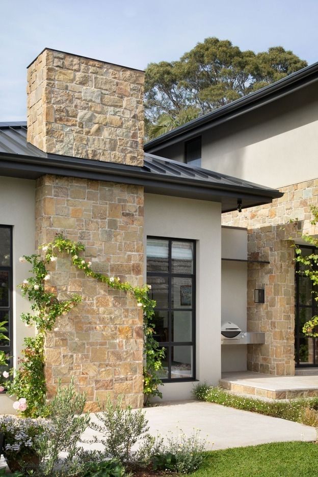 Renovated home exterior with pale brick, black-framed windows and dark vertical cladding