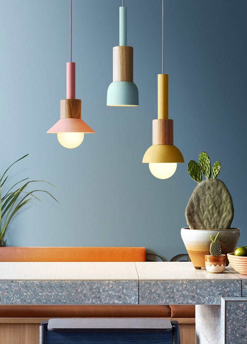 Dining room with a pale blue feature wall, black pendant lights on cables and teak chairs beside a wooden platform